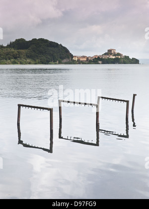 Il lago di Bolsena con acqua la riflessione e il piccolo villaggio di Capodimonte, Italia centrale Foto Stock