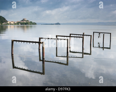 Il lago di Bolsena con acqua la riflessione e il piccolo villaggio di Capodimonte, Italia centrale Foto Stock