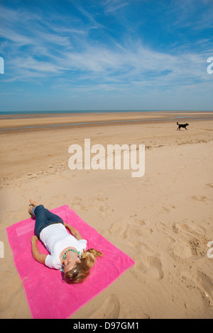 GB; Regno Unito; Inghilterra; NORFOLK; THORNHAM; Spiaggia; donna; prendere il sole; da soli; Spiaggia Foto Stock