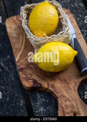 Due limoni interi su un legno di ulivo tagliere Foto Stock