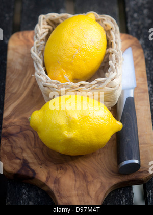 Due limoni interi su un legno di ulivo tagliere Foto Stock