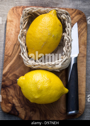 Due limoni interi su un legno di ulivo tagliere Foto Stock