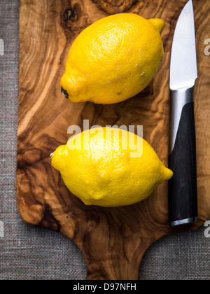 Due limoni interi su un legno di ulivo tagliere Foto Stock