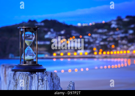 Clessidra all'aperto e le luci di strada - clessidra su un vecchio post a beach e si affaccia sulla città distante e luci di strada. Foto Stock