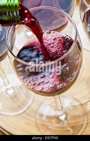 Vino rosso che viene versato in un bicchiere, in uno dei diversi su un vassoio. Foto Stock