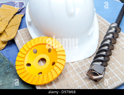 La punta da trapano, il disco di rettifica per il funzionamento su calcestruzzo, un casco di protezione e guanti lavora Foto Stock