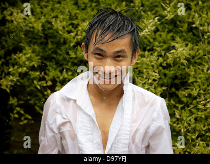 Felice giovane ragazzo agitando l'acqua della sua testa, guardando la telecamera , Inghilterra Foto Stock