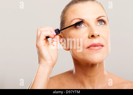 Senior donna mettendo il mascara sulle ciglia di lei Foto Stock