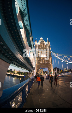 Tower Bridge Pedestrian Walkway Londra Inghilterra // LONDRA, Regno Unito — l'iconico Tower Bridge attraversa il Tamigi nel centro di Londra, con questa vista che cattura il passaggio pedonale e una delle sue caratteristiche torri neogotiche al tramonto. Completato nel 1894, il bascule combinato e il ponte sospeso presenta il montante di supporto blu visibile sulla sinistra, parte della distintiva ingegneria vittoriana del ponte. Il Tower Bridge collega la City di Londra sulla riva nord con Southwark sulla riva sud e rimane uno dei punti di riferimento più riconoscibili della città. Il ponte è alto 213 piedi (65 m Foto Stock