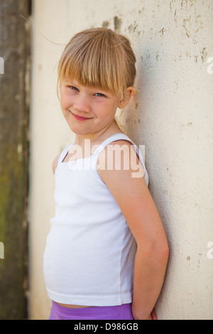 Ritratto di carino sorridente ragazza appoggiata contro la parete di cemento Foto Stock