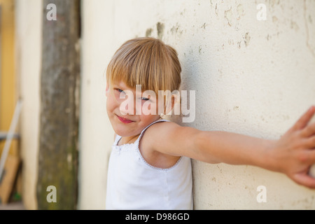 Ritratto di carino ragazza giovane con il braccio disteso contro il muro di cemento Foto Stock