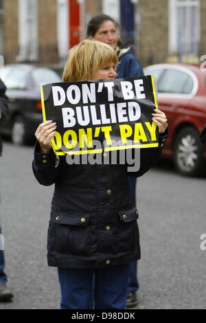 Dublino, Irlanda. 14 giugno 2013. Un anti-famiglia tax protester detiene una targhetta che legge'Do non essere vittima di bullismo, non paga". Anti-tassa di uso domestico e anti-JobBridge manifestanti picketed il Ministro per la protezione sociale Joan Burton (Manodopera) durante la sua visita in un ufficio della nazionale irlandese di organizzazione dei disoccupati (INOU), chiamandola ad abolire la tassa per uso domestico e il tirocinante regime. Credito: Michael Debets/Alamy Live News Foto Stock