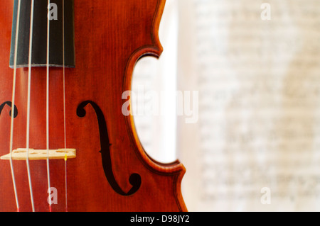 Dettaglio di un bellissimo violino con un sfocato spartito musicale in background. Foto Stock