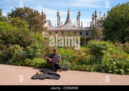 Un senzatetto, musicista di strada da suonare la chitarra attraverso un amplificatore portatile, in un parco vicino al Padiglione di Brighton, Inghilterra, Regno Unito. Foto Stock