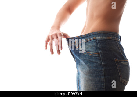 Giovane donna dietologia e contemplando la perdita di peso che indossa jeans camice su sfondo bianco Foto Stock