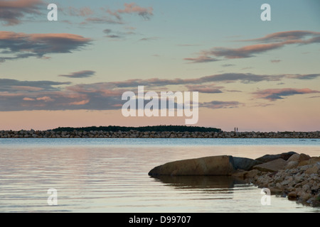 Alba su Oak Island, Nova Scotia, con due persone a piedi lungo il muro frangiflutti. Foto Stock