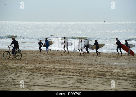 Gruppo di persone in esecuzione con tavole da surf, Scheveningen, Paesi Bassi Foto Stock