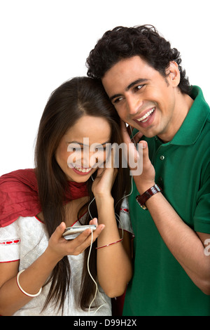 Matura per ascoltare musica su un telefono cellulare e sorridente Foto Stock