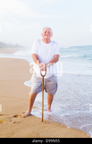 Senior man tenendo un bastone da passeggio sulla spiaggia Foto Stock