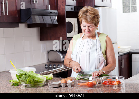 Donna anziana la cottura di cibi in cucina domestica Foto Stock