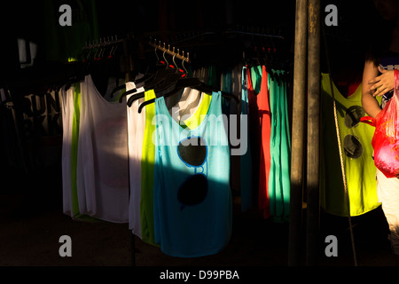 WAT MERCATO KARON, KARON, Phuket, Thailandia Febbraio 16 2013: Donna cammina da display di T-shirt e canottiere al mercato del Tempio Foto Stock