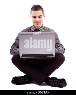 A piena lunghezza pongono del giovane imprenditore seduto sul pavimento e la scrittura sul suo laptop, isolato su sfondo bianco Foto Stock