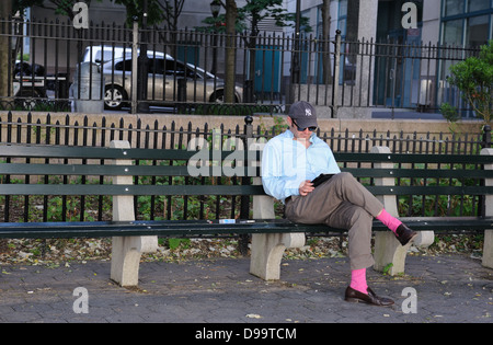 Un uomo di lettura sul Battery Park City esplanade in Lower Manhattan. Foto Stock