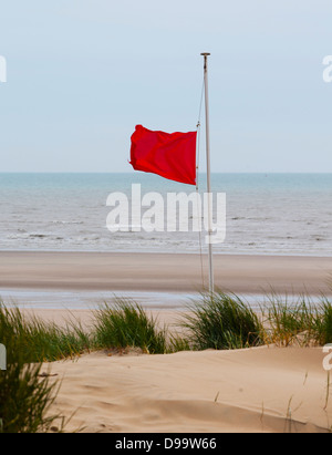 Una bandiera rossa di avvertimento di pericolose condizioni di acqua sulla spiaggia di camber sands, segale, east sussex. Foto Stock