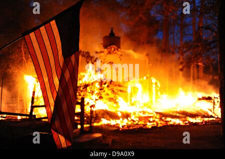 Una bandiera americana si blocca nella parte anteriore di una masterizzazione home come la Foresta Nera wildfire devastazioni case Giugno 12, 2013 vicino a Colorado Springs, CO. Giugno 12, 2013. Due persone sono state uccise e più di 500 case distrutte. Foto Stock