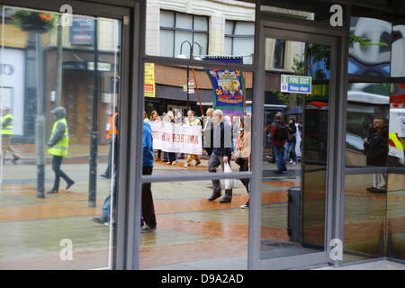 Belfast, Regno Unito. Il 15 giugno 2013. La riflessione del passaggio di marzo è visto nella vetrina di un negozio. Sindacalisti hanno marciato attraverso Belfast in vista del vertice G8 che si terrà in Irlanda del Nord. Gli organizzatori hanno chiamato per una sfida all'ordine del giorno del vertice, chiamando il frequentare i leader del mondo per promuovere un mondo più giusto per tutti. Credito: Michael Debets/Alamy Live News Foto Stock