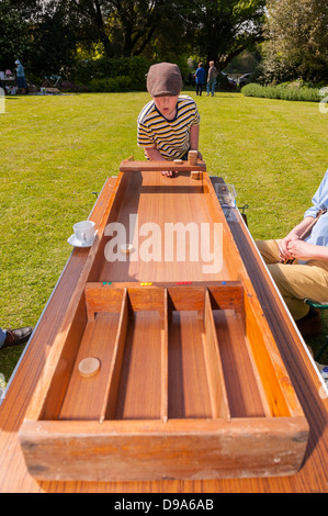 Un ragazzo giocando Sjoelbak in un villaggio di fete e giardini aperti a Sotterley Hall di Sotterley , Suffolk , Inghilterra , Inghilterra , Regno Unito Foto Stock