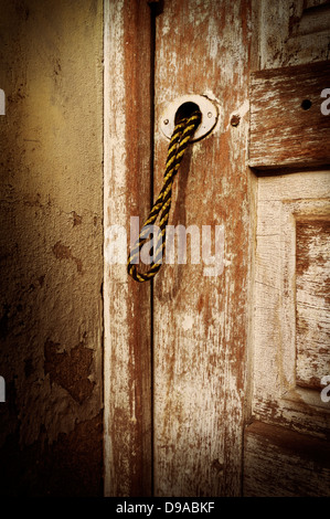 Porta vecchia trascurato, vernice sbiadita con stringa tirare la maniglia Foto Stock