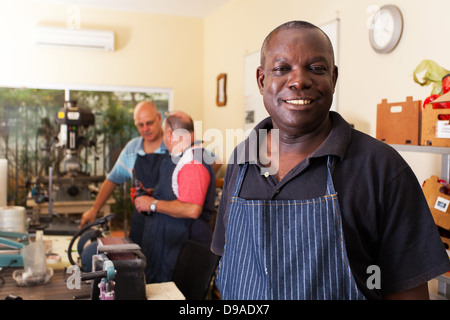 Senior metallo africani lavoratore in officina con i colleghi Foto Stock