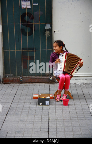 Bambina a suonare la fisarmonica mentre sorridente su strada Foto Stock