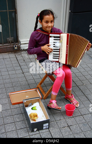 Bambina a suonare la fisarmonica mentre sorridente su strada Foto Stock