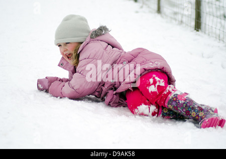 Giovane ragazza che è caduto nella neve Foto Stock