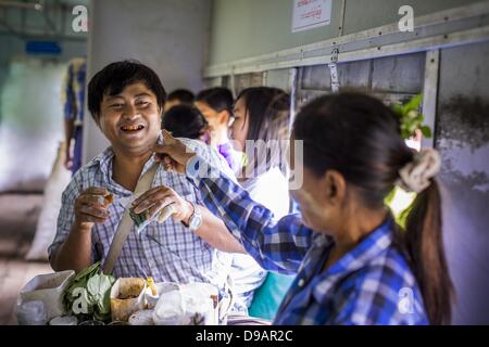 Yangon, Unione di Myanmar. Il 15 giugno, 2013. Un fornitore di betel, sinistra, barzellette con un cliente a Yangon treno circolare. L Arcidiocesi di Yangon ferroviaria circolare è il locale dei pendolari rete ferroviaria che serve il Yangon area metropolitana. Azionato da Myanmar Ferrovie, 45,9-chilometro (28.5Â mi) 39-stazione di sistema ad anello collega città satelliti e zone di periferia della città. La ferrovia ha circa 200 autobus, esegue 20 volte e vende 100.000 a 150.000 biglietti giornalieri. Il loop che richiede circa tre ore per completare, è un popolare per i turisti a vedere una sezione della vita di Yangon. I treni da 3:45 am Foto Stock