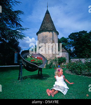 Le Château de la Berchère. Un grazioso, cinque anni ragazza bionda, in un abito bianco, seduto da solo nel giardino di un chateau hotel in Borgogna, Francia. Foto Stock