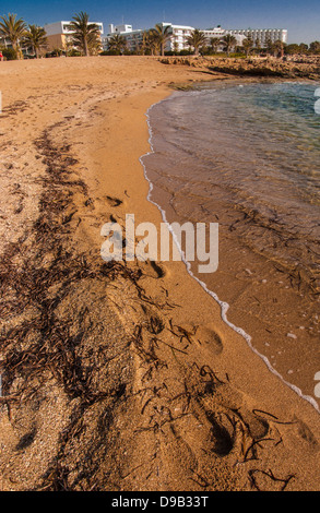 Spiaggia e mare in primo piano con hotel e appartamenti in bianco sullo sfondo. Foto Stock