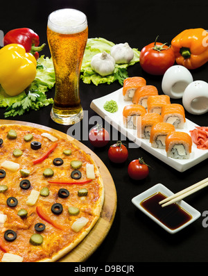 Composizione della birra sushi e pizza su sfondo nero Foto Stock