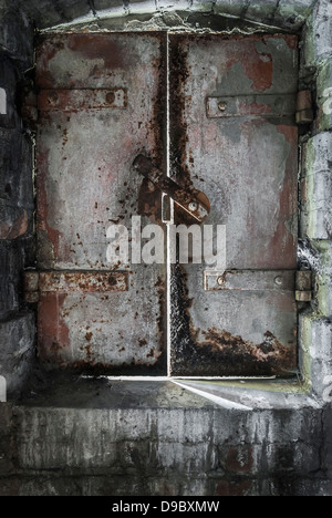 Un vecchio, ruggine ghisa porta dungeon lasciando in fessure di luce del sole. Foto Stock