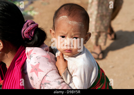 Pa-O baby volto dipinto con pasta thanakha espulso sulla sua madre torna in un mercato in Myanmar (Birmania) Foto Stock