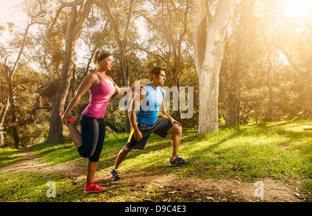 Due persone che esercitano nella foresta facendo il warm up si allunga Foto Stock