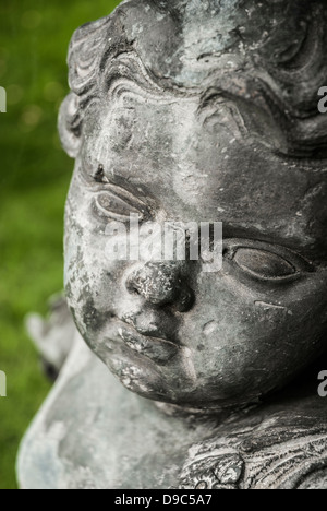 Particolare del volto di una pietra ornamentali giardino cherubino statua. Foto Stock