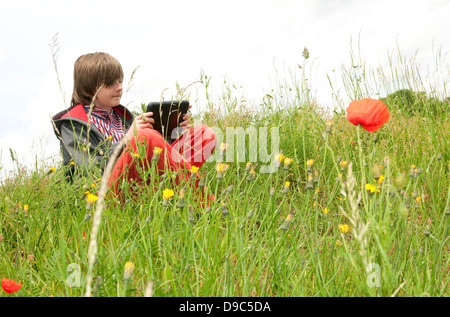 ragazzo di sesso maschile che utilizza un computer ipad mini tablet in campagna Foto Stock