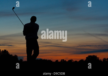 Silhouette di un giocatore di golf solitario finitura di una partita a golf al crepuscolo Foto Stock