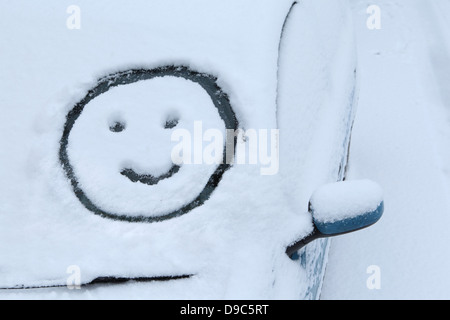 Smiley face tracciata nella neve sul parabrezza per auto Foto Stock