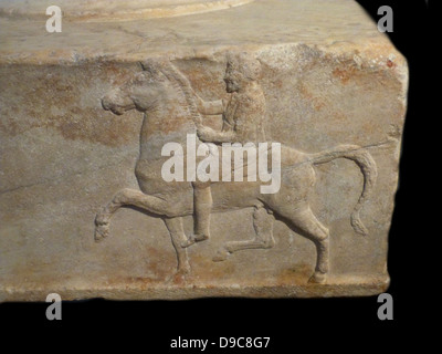 Base di una dedizione nel marmo. Riscontrato nell'agora ateniese. Base di una dedizione per le vittorie in simulazioni di combattimento di cavalleria contest. Tre lati di esso hanno rilievi raffiguranti un cavaliere in sella verso un treppiede. L'iscrizione sul quarto lato fornisce i nomi della vittoriosa dedicators e anche quello dello scultore Bryavis che ha scolpito il monumento. Essa avrà sostenuto un tripode in bronzo dedicato dai vincitori. Metà del IV secolo A.C. Foto Stock