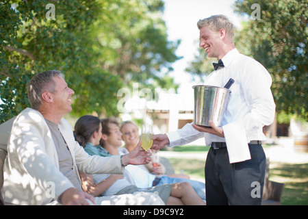 Cameriere serve clienti in giardino Foto Stock