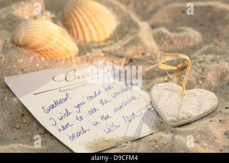 Cuore con la Postcard e conchiglie di mare sulla spiaggia Foto Stock